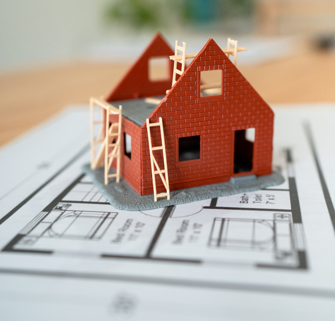 Modell eines zu renovierenden Hauses in Dortmund steht auf einem Bauplan