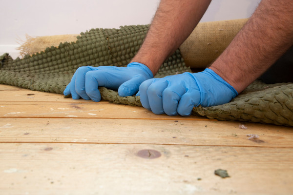 Ein Handwerker entfernt einen Teppichboden in Bochum