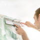 Tapezierer schneidet die Tapete an der Decke mit dem Messer ab